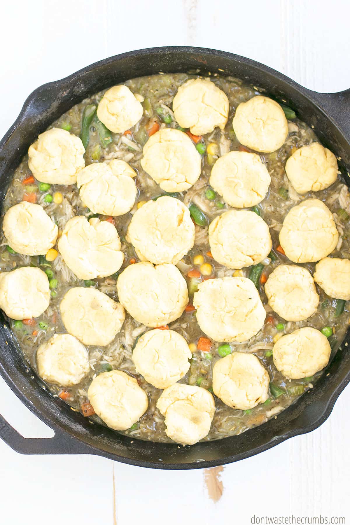 Homemade chicken pot pie with homemade biscuits on top in a cast iron skillet