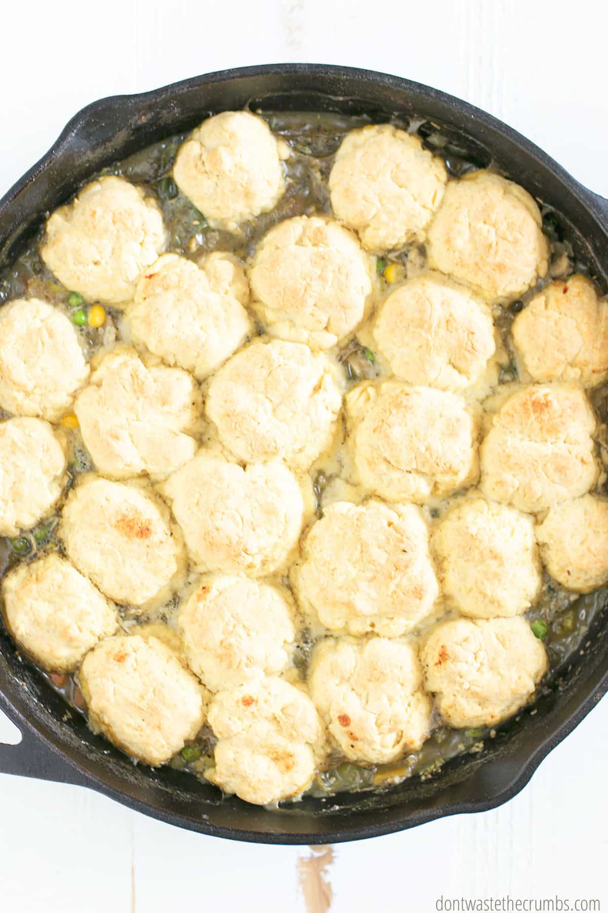 Chicken pot pie with homemade biscuits on top in a cast iron skillet