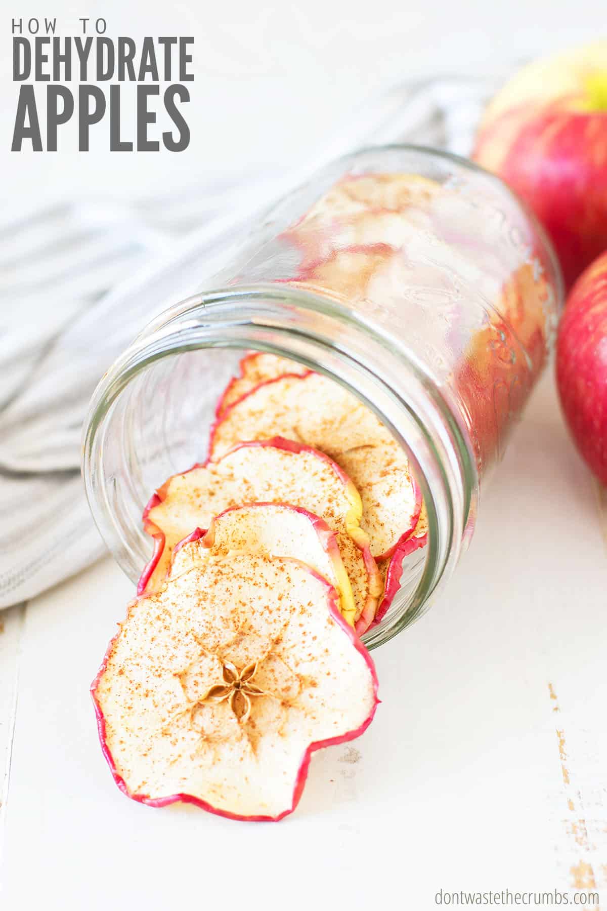 dried apples in a mason jar on a table with text overlay how to dehydrate apples