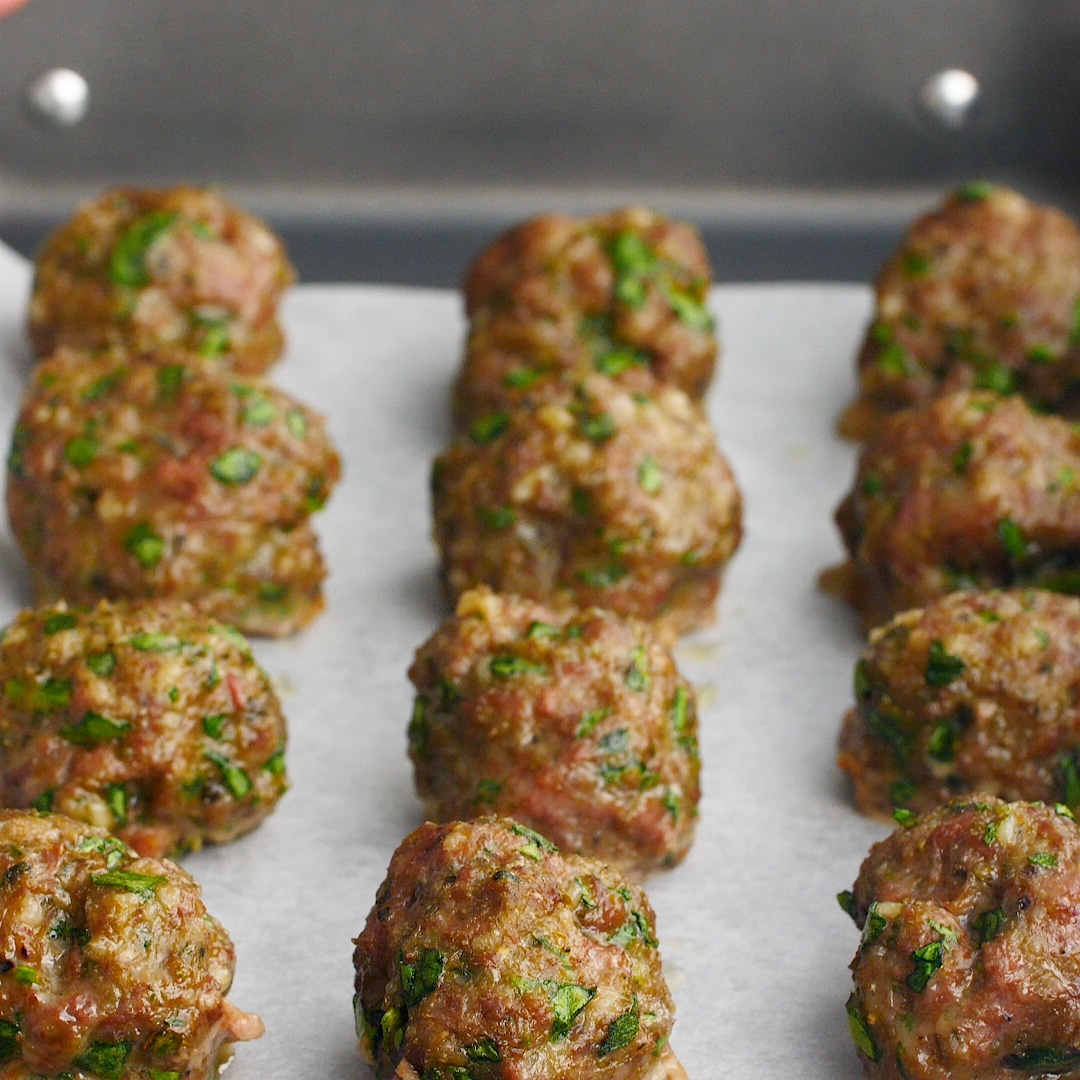 Homemade meatballs fresh out of the oven on a lined baking sheet