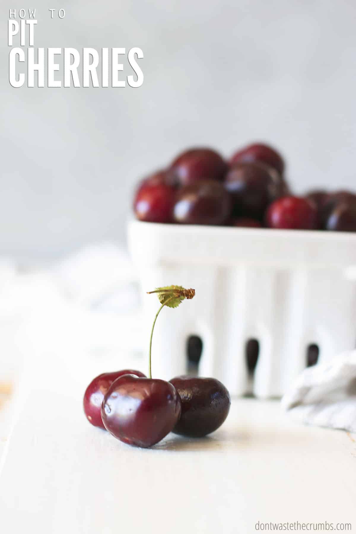 Three cherries and a white square bowl of a bunch of cherries. Text overlay How to Pit Cherries