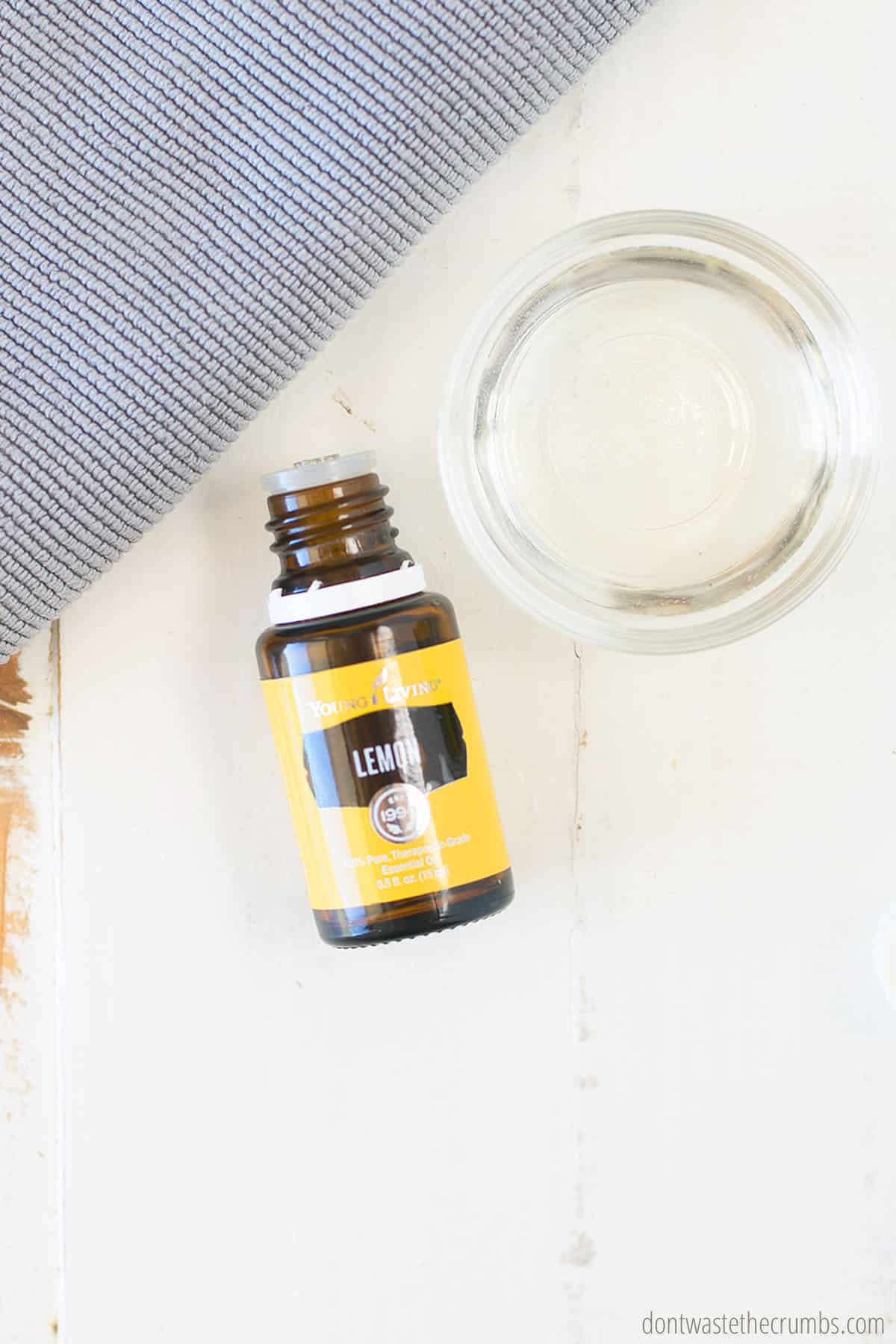 Opened bottle of lemon essential oil and small glass bowl