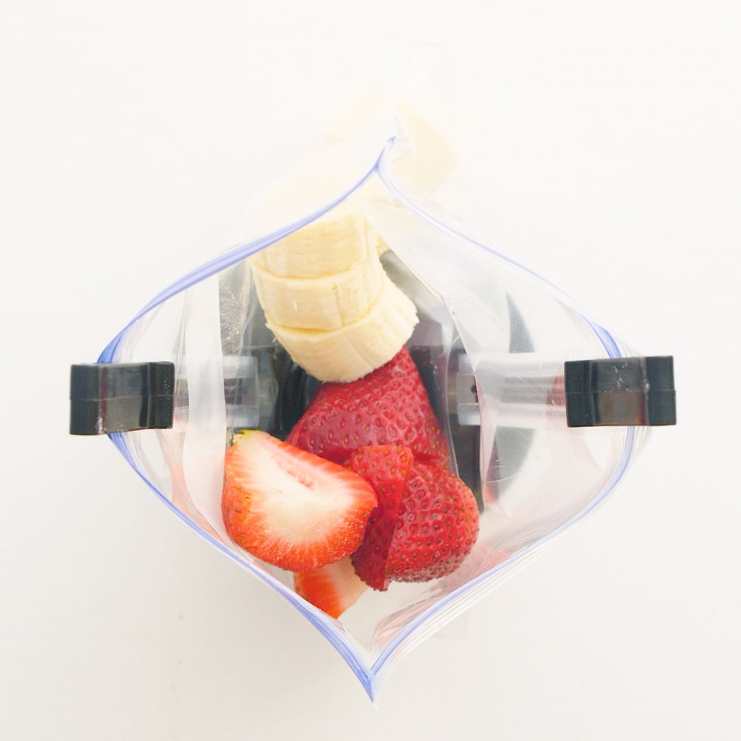Big chunks of banana and strawberries in a ziplock bag that is being held open with a baggy holder