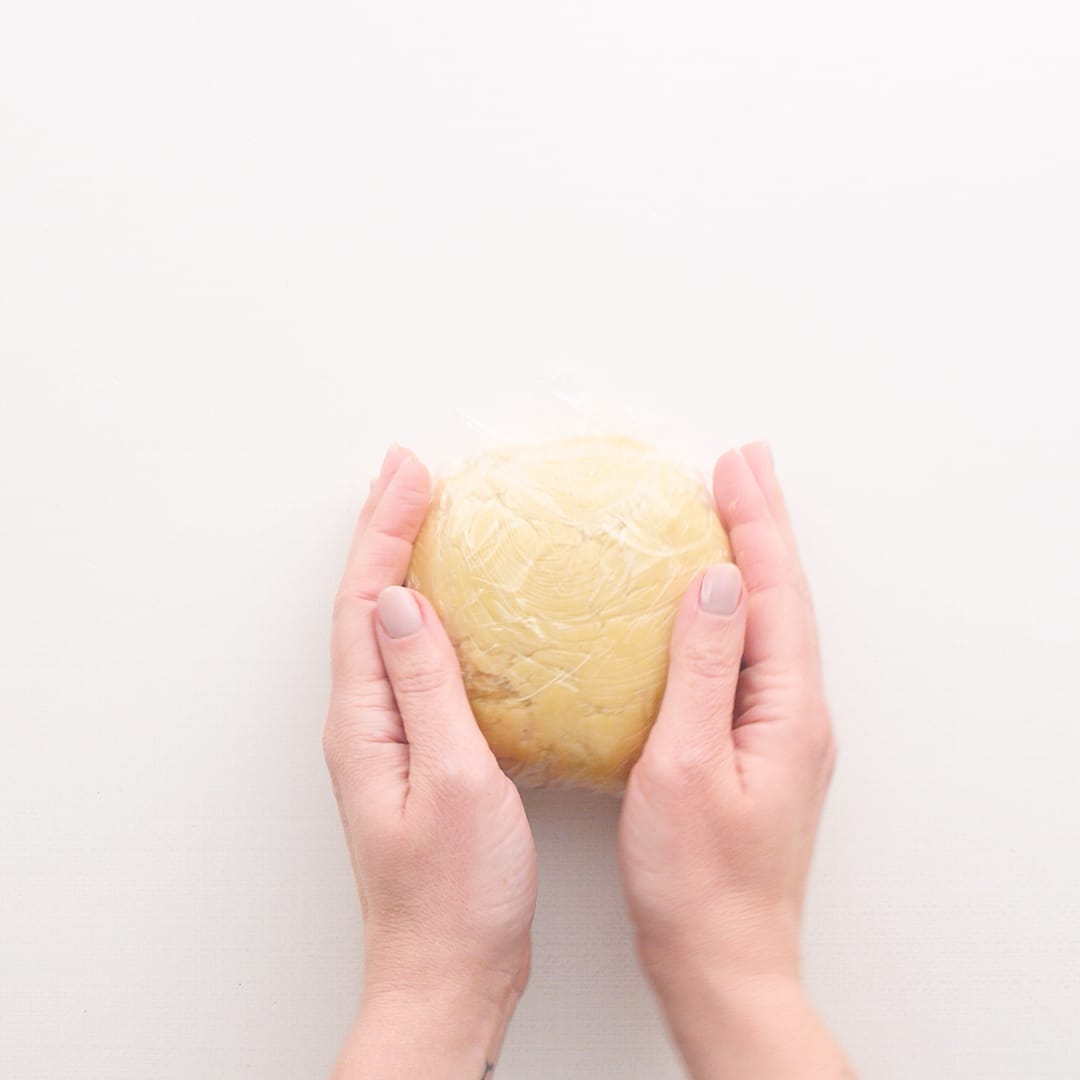 Hands holding chilled ball of sugar cookie dough