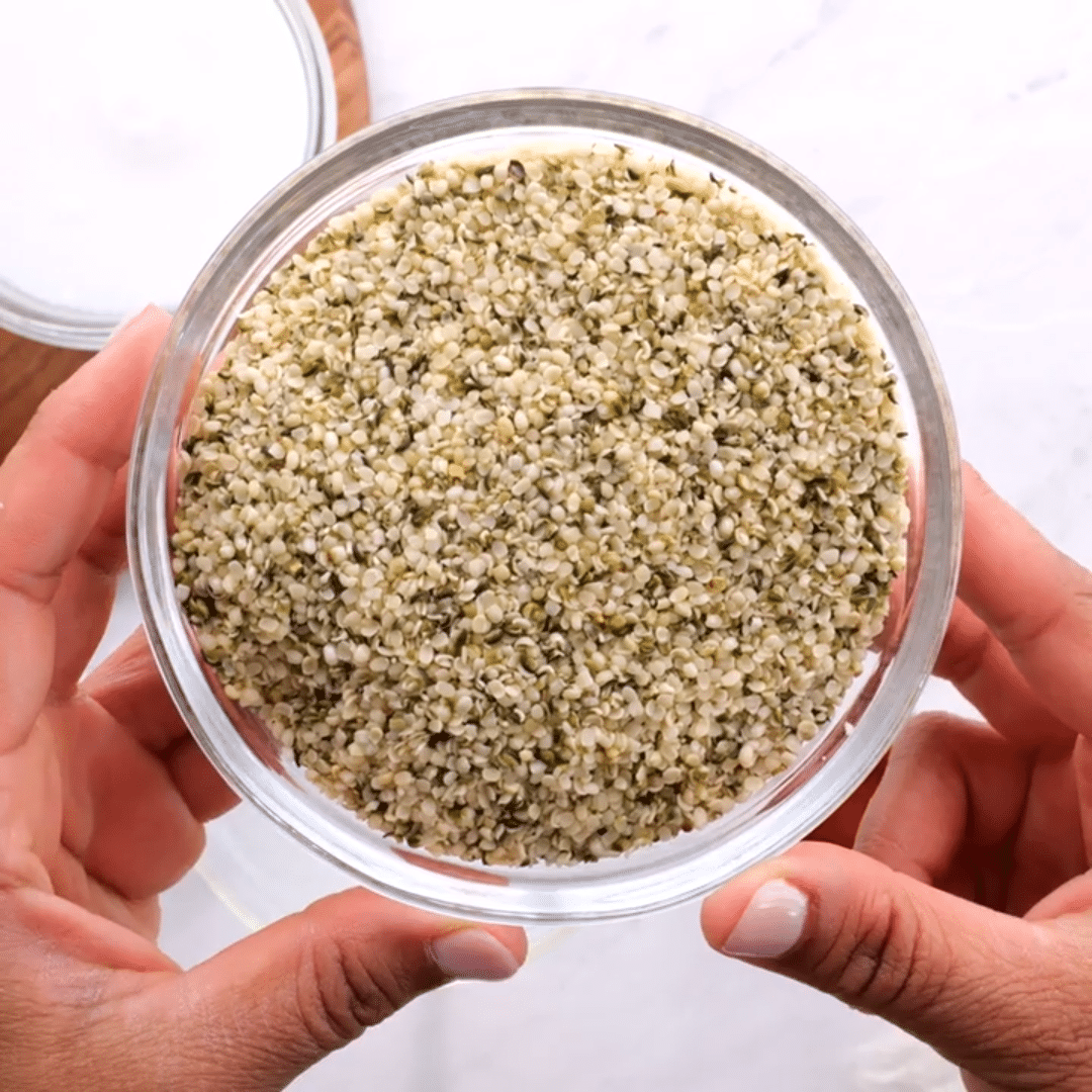 Hands holding a glass bowl with hemp seeds