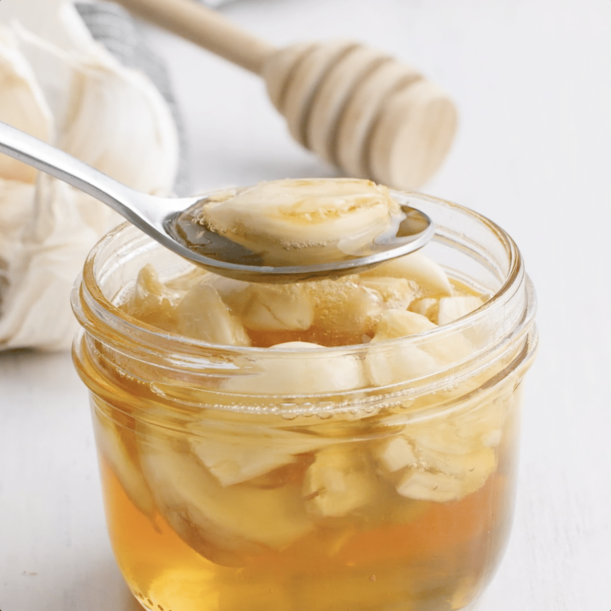 Spoon scooping out crushed garlic from a mason jar full of honey and garlic