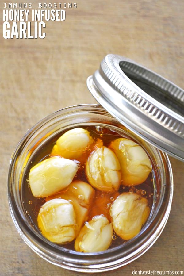 Honey garlic in a mason jar with the lid laying against the jar. Text overlay reads: Immune Boosting Honey Infused Garlic