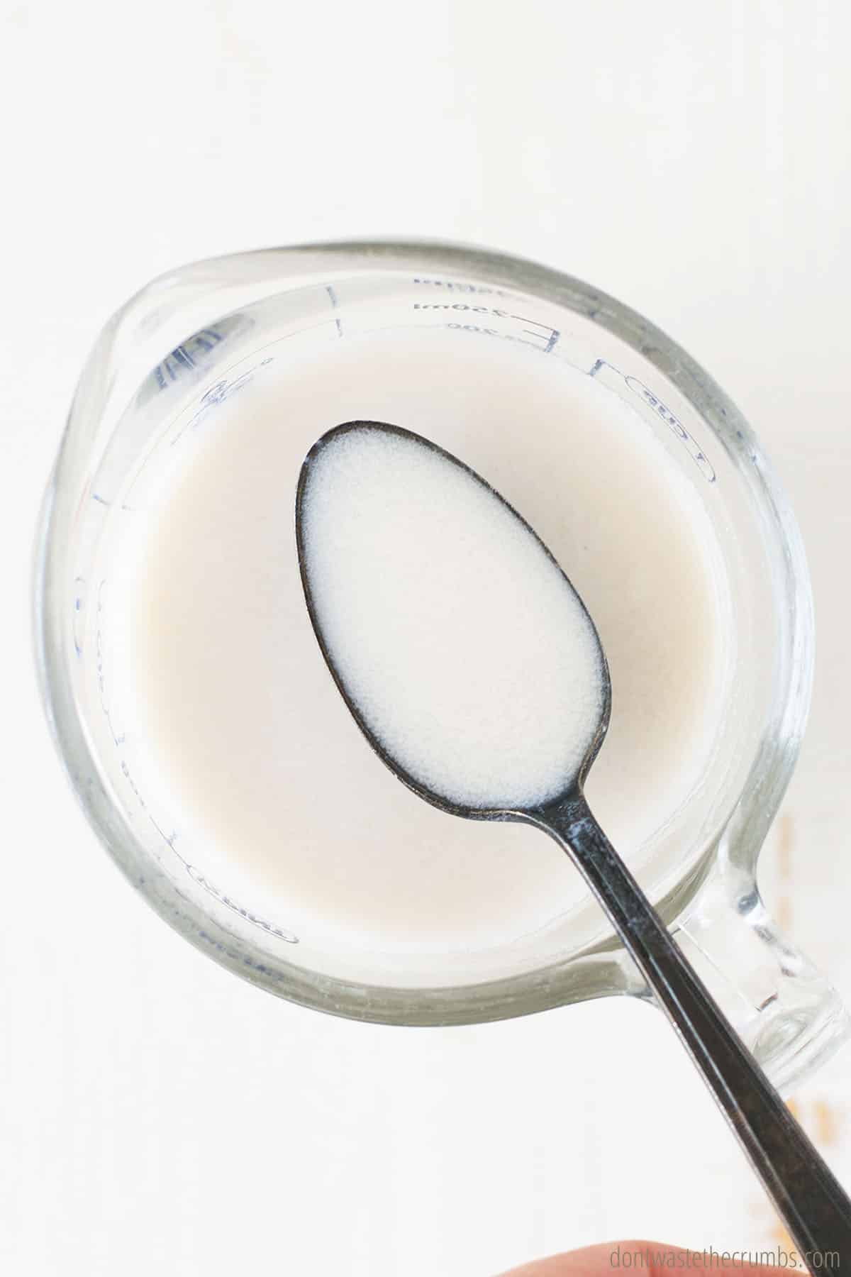 Homemade buttermilk in a measuring cup with a spoon full of the mixture