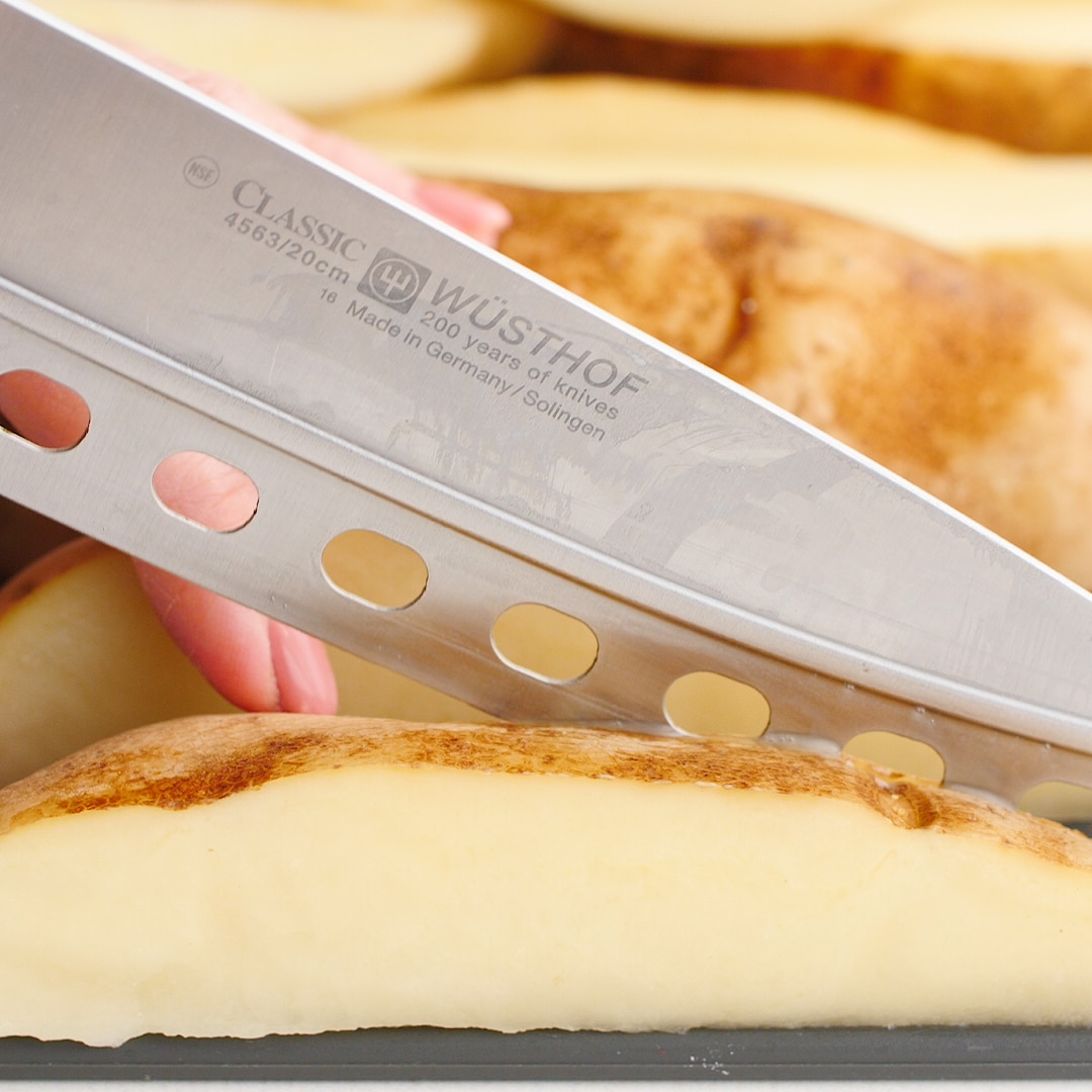 Sharp knife cutting lengthwise on a potato