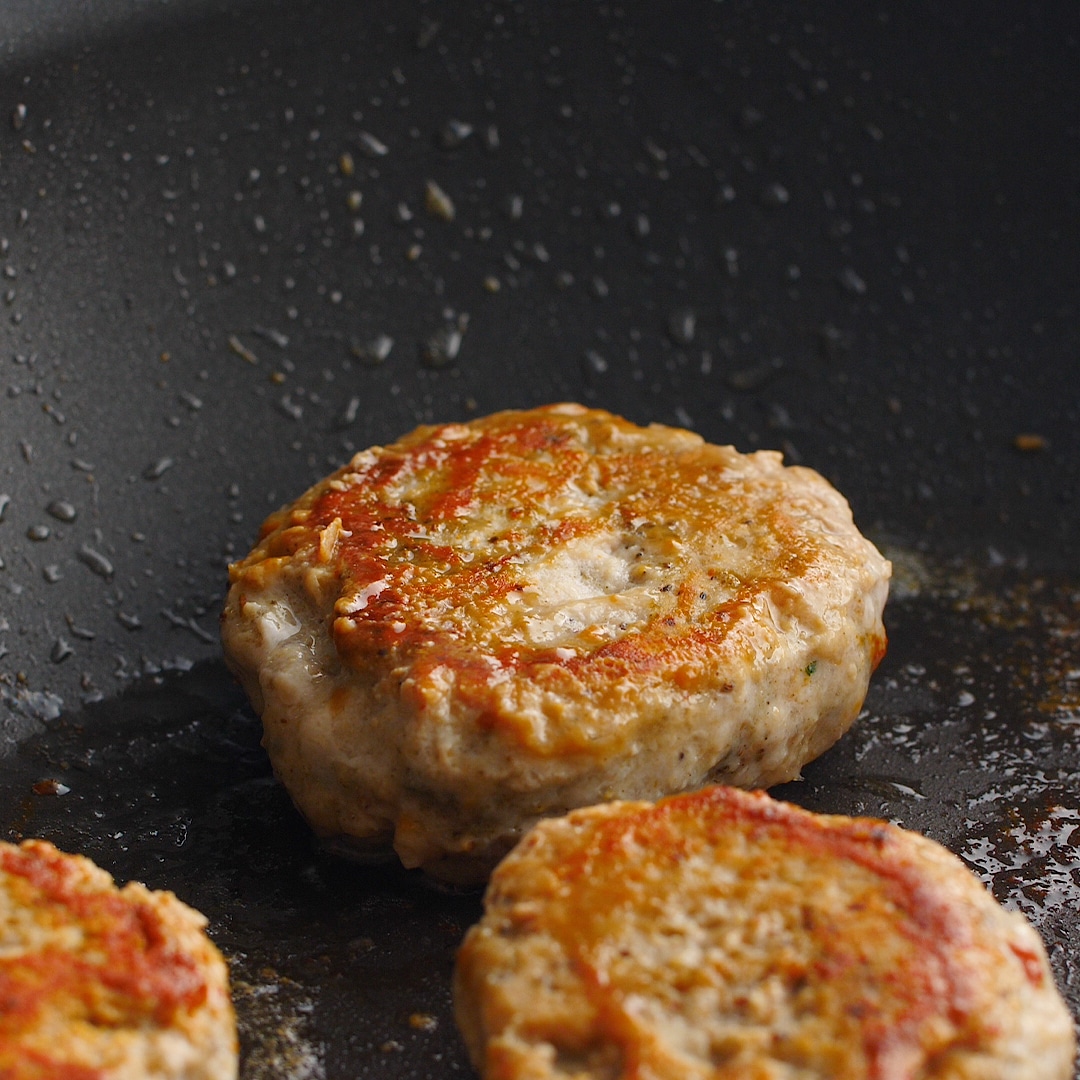 Sausage patties cooking in a cast iron skillet