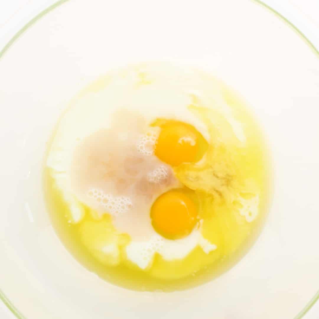 Eggs, milks, vanilla in a large glass bowl.