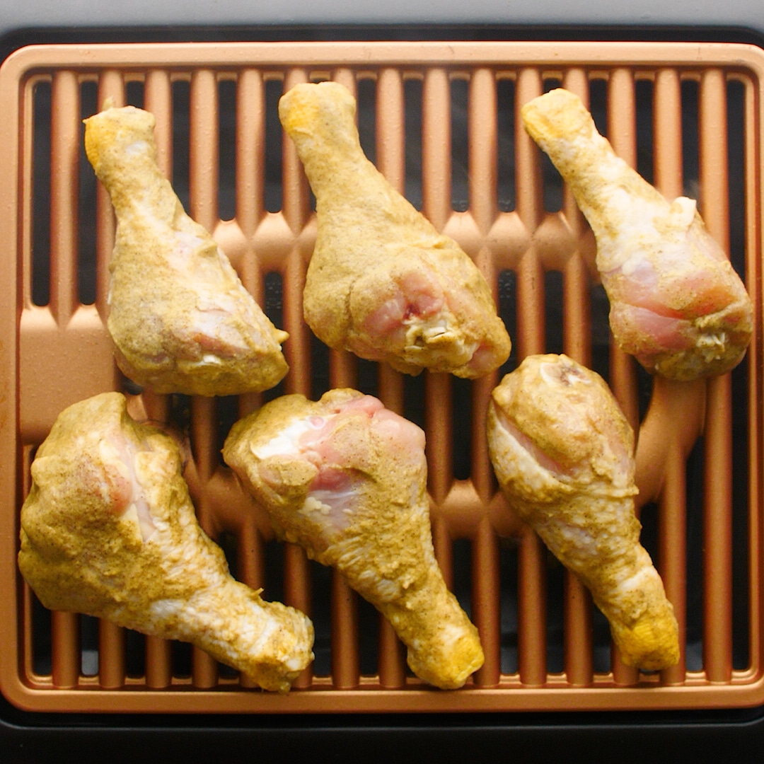 6 chicken drumsticks with seasoning on a grill