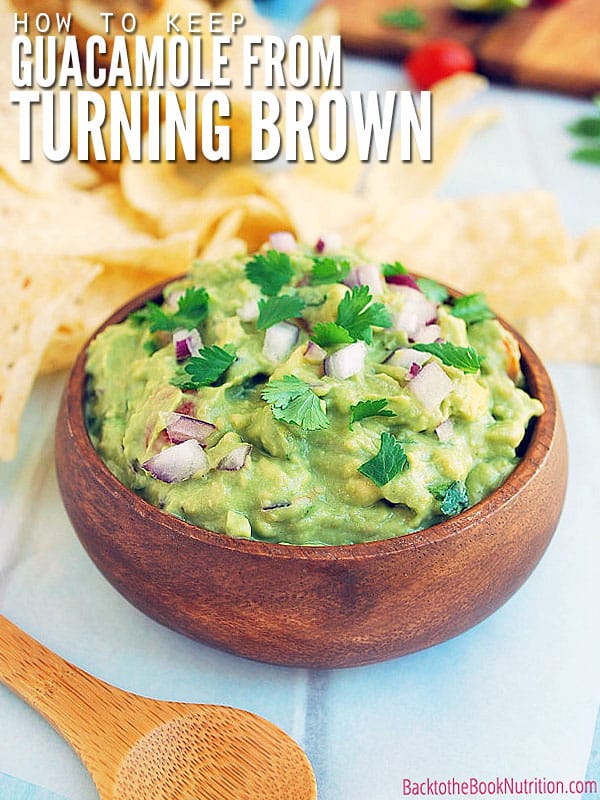Homemade guacamole in a wood bowl with tortilla chips nearby. Text overlay reads, "How to keep guacamole from turning brown"