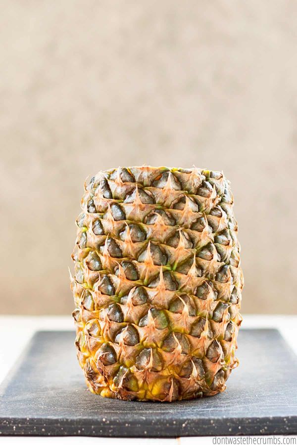 Here is a whole pineapple with the leafy  tops and the bottom cut off.