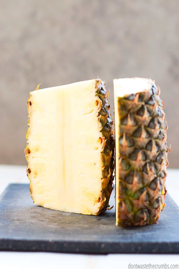 A whole pineapple cut in half with the skin on and the top and bottom and cut off.