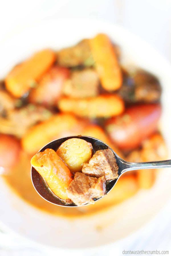 This Instant Pot beef stew is in a glass white bowl and an up close view of a spoonful portion.