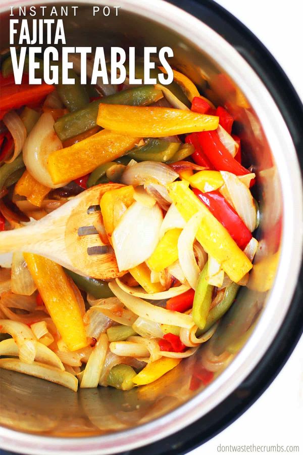 Sliced bell peppers and sliced onions inside of an instant pot stirred with a slotted wooden spoon. The text overlay reads, "Instant Pot Fajita Vegetables."