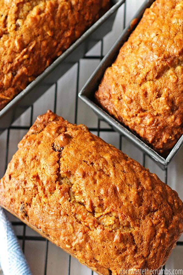 Three spiced carrot breads in loaf pans on a cooling rack.