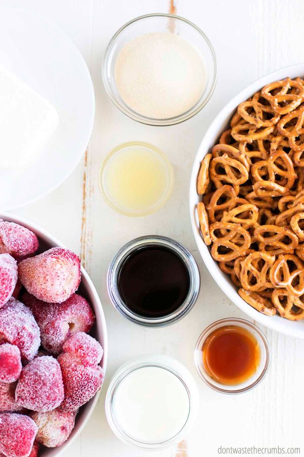 Ingredients for strawberry pretzel salad set out in individual bowls on a table. pretzels, frozen strawberries, maple syrup, cream cheese, lemon juice, gelatin, cream