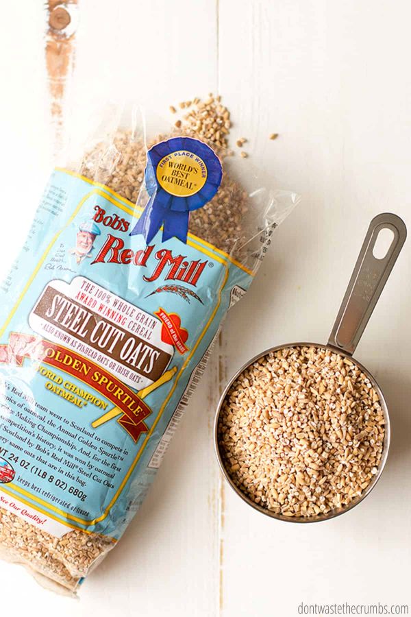 A bag of Bob's Red Mill Steel Cut Oats sits next to a measuring cup filled with oats.